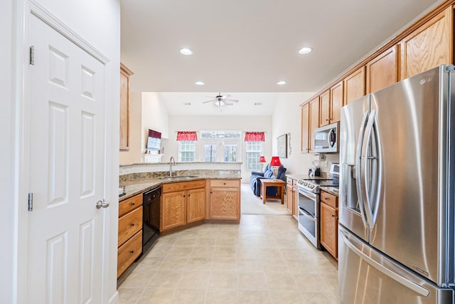 kitchen featuring stainless steel appliances, a peninsula, a sink, open floor plan, and a ceiling fan