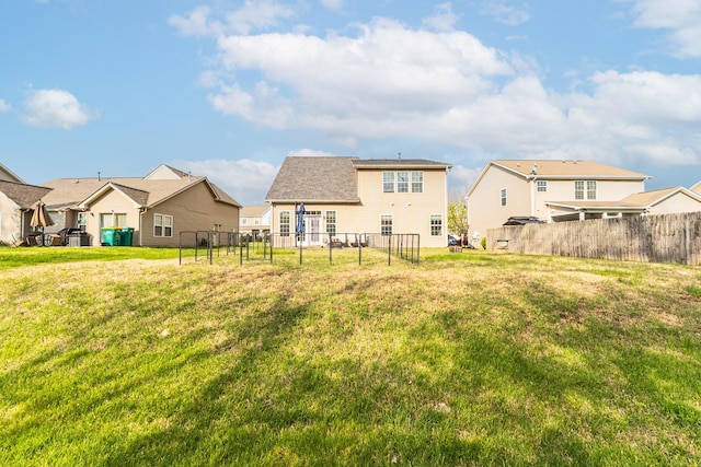 rear view of property featuring fence, a lawn, and a residential view