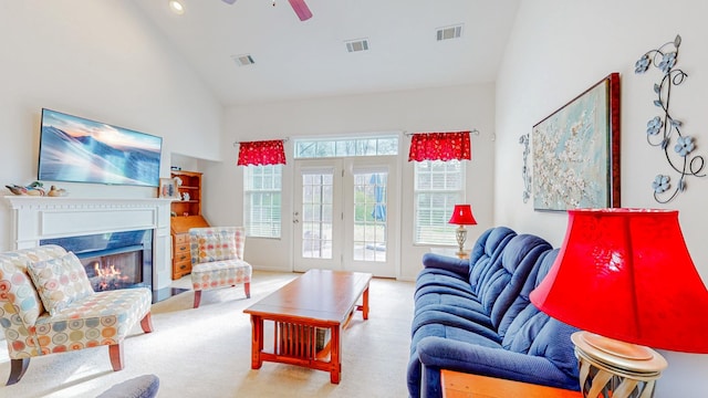 living area featuring a warm lit fireplace, a ceiling fan, and visible vents
