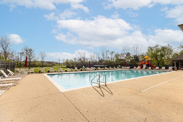 pool with a patio area, fence, and playground community