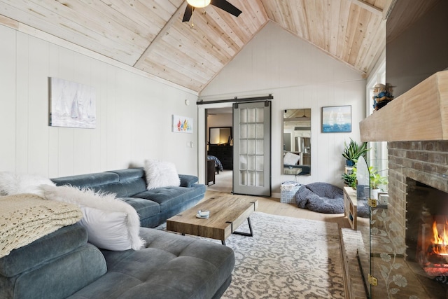 living area featuring a barn door, wood finished floors, wood ceiling, ceiling fan, and a fireplace