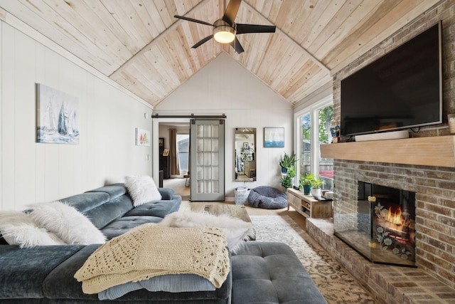 living room with lofted ceiling with beams, a barn door, ceiling fan, wooden ceiling, and a fireplace