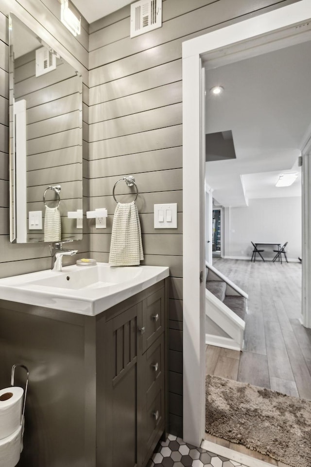 bathroom featuring vanity, wood finished floors, and wooden walls