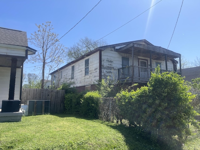 view of home's exterior with a lawn, a balcony, and fence