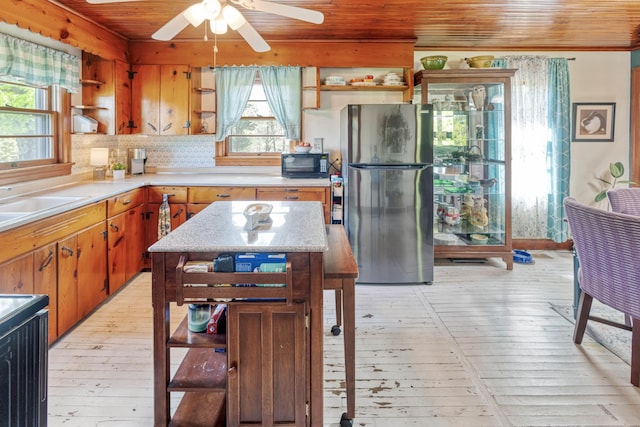 kitchen with open shelves, freestanding refrigerator, light wood-type flooring, and wooden ceiling