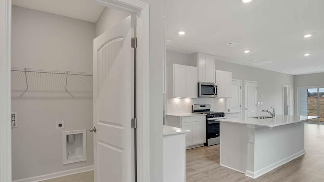 kitchen with backsplash, appliances with stainless steel finishes, a sink, and white cabinetry