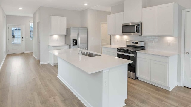 kitchen featuring stainless steel appliances, light wood-style flooring, a kitchen island with sink, and a sink