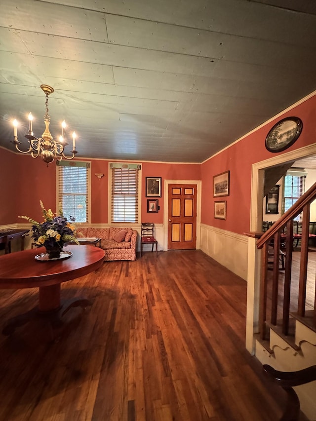 interior space featuring plenty of natural light, a wainscoted wall, dark wood-style floors, and an inviting chandelier