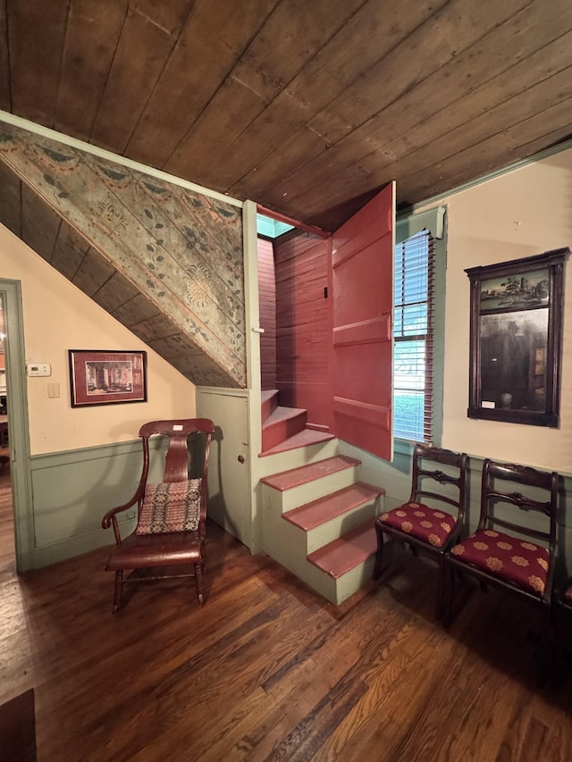 living area featuring vaulted ceiling, wood finished floors, wooden ceiling, wainscoting, and stairs