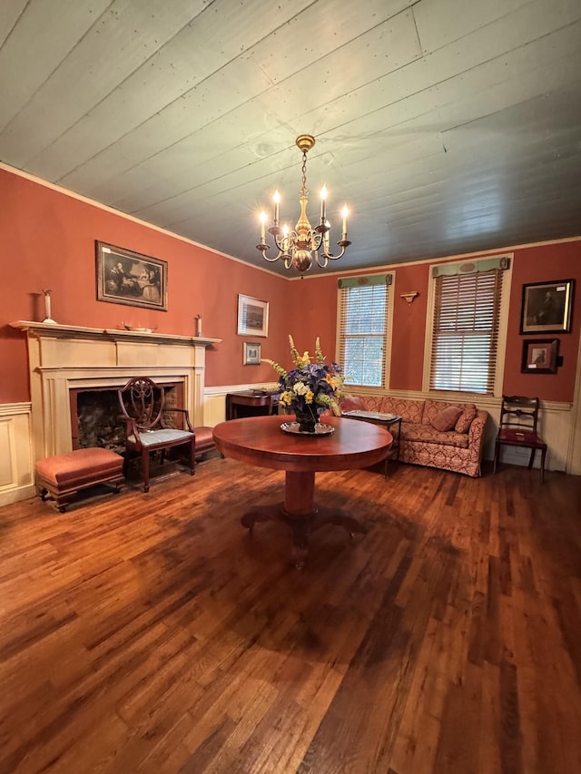 dining space featuring an inviting chandelier, crown molding, wainscoting, a fireplace, and hardwood / wood-style flooring