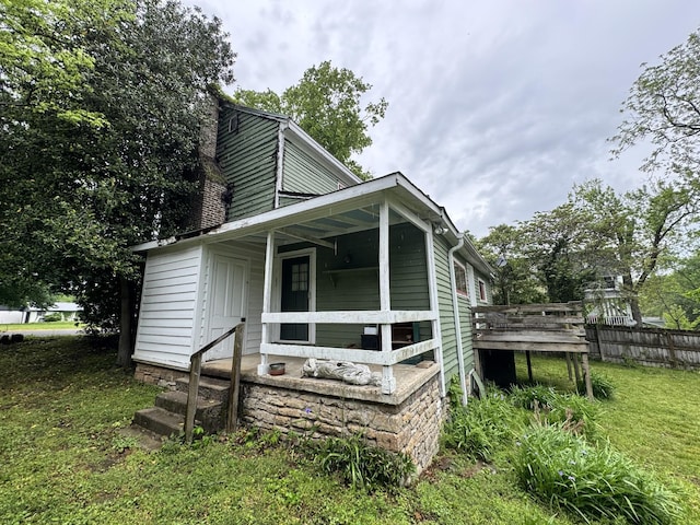 view of property exterior with a lawn, fence, and a porch