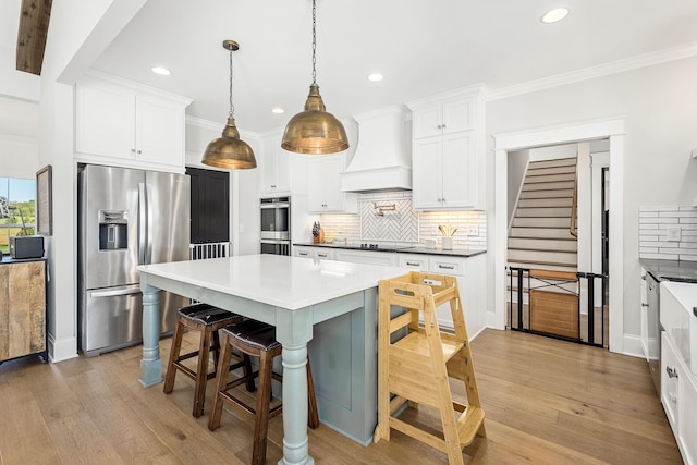 2040 Cairo Bend Rd, Lebanon, TN 37087 - kitchen featuring tasteful backsplash, custom range hood, appliances with stainless steel finishes, light wood-type flooring, and a kitchen breakfast bar
