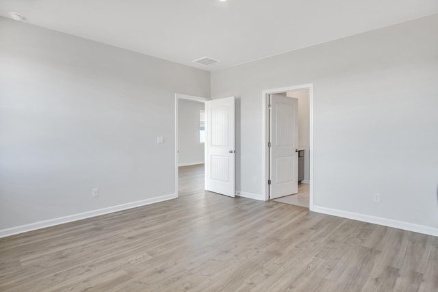 empty room featuring baseboards, visible vents, and light wood-type flooring