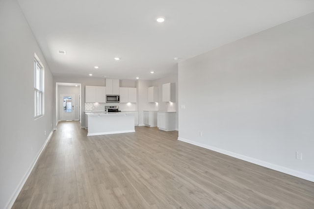 unfurnished living room with light wood-type flooring, baseboards, and recessed lighting