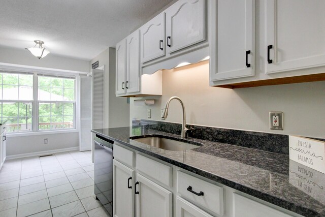 3473 Hunters Rdg, Woodlawn, TN 37191 - kitchen featuring stainless steel dishwasher, a sink, light tile patterned floors, dark stone counters, and white cabinetry