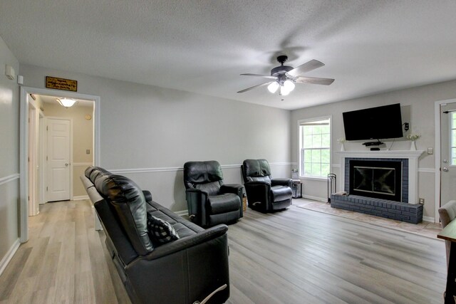 3473 Hunters Rdg, Woodlawn, TN 37191 - living room with a fireplace, light wood-style floors, baseboards, ceiling fan, and a textured ceiling