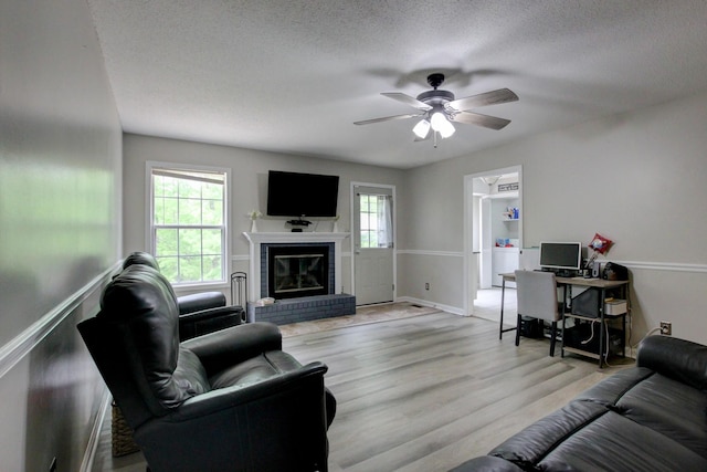 3473 Hunters Rdg, Woodlawn, TN 37191 - living room featuring ceiling fan, a brick fireplace, light wood-type flooring, and a textured ceiling