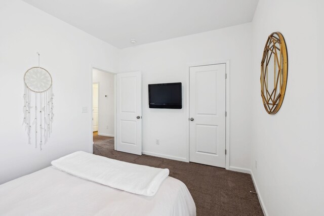 bedroom featuring dark colored carpet and baseboards