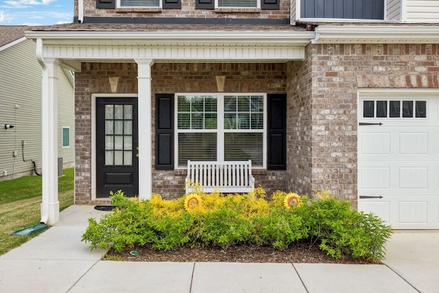 property entrance featuring brick siding, an attached garage, and covered porch