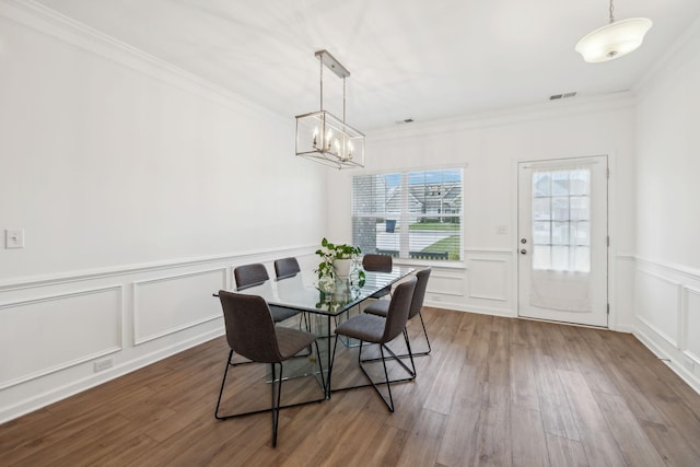 dining room with a notable chandelier, a decorative wall, crown molding, and visible vents