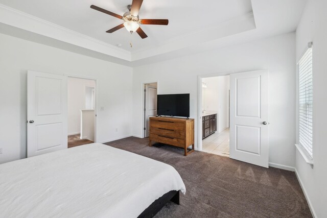 bedroom featuring crown molding, connected bathroom, carpet floors, a tray ceiling, and baseboards