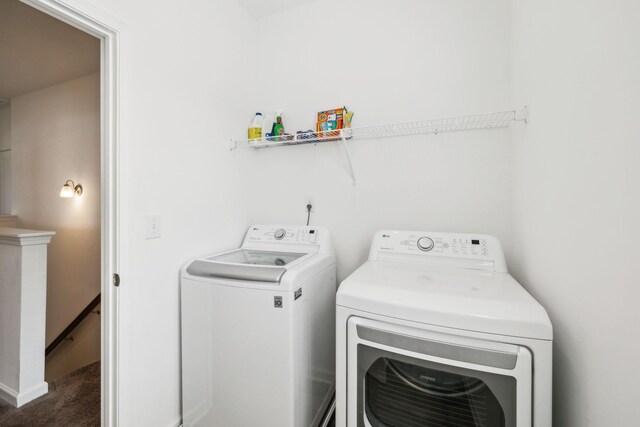 clothes washing area with washing machine and dryer, carpet floors, and laundry area