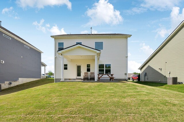 back of house with a patio area, a lawn, and central AC