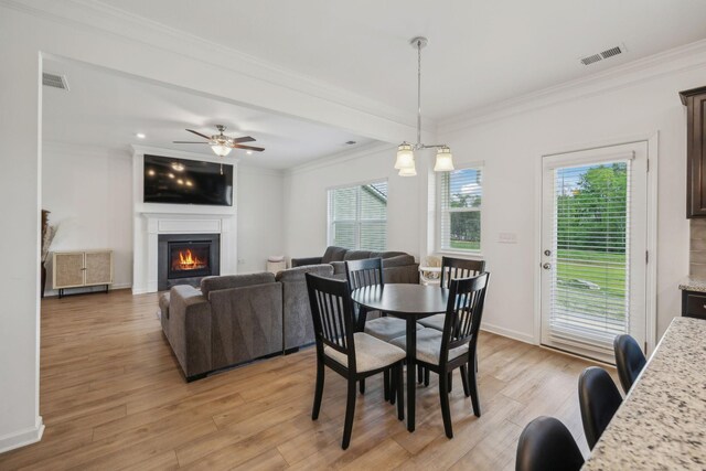 dining space featuring light wood finished floors, visible vents, a wealth of natural light, and a lit fireplace