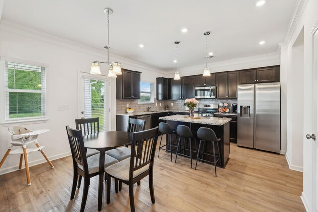 dining space featuring light wood-type flooring and crown molding