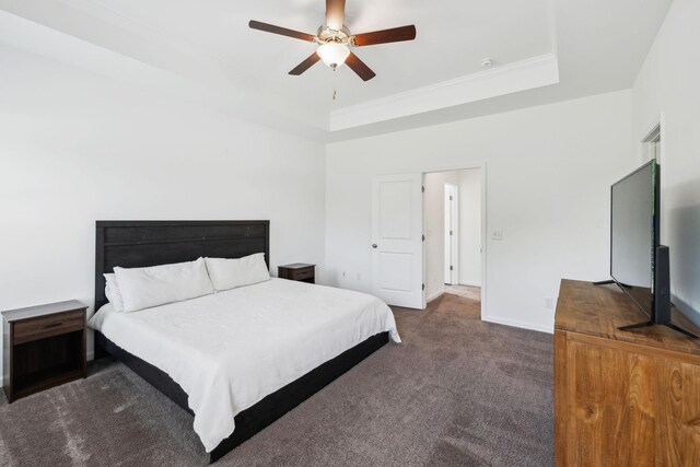 carpeted bedroom featuring ceiling fan, baseboards, a raised ceiling, and crown molding
