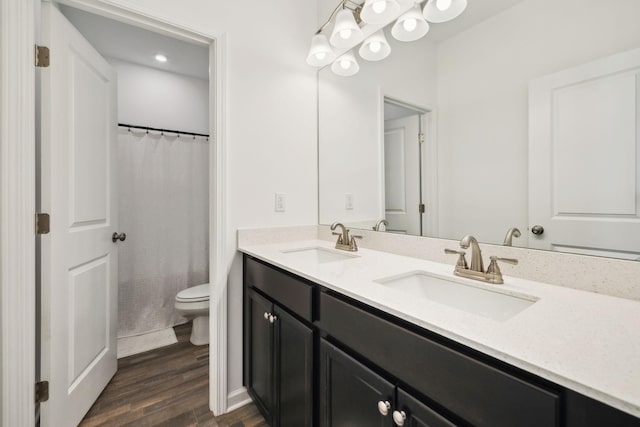 full bathroom featuring double vanity, wood finished floors, toilet, and a sink