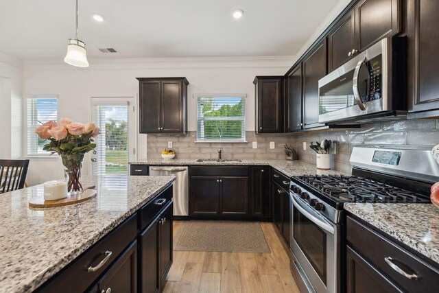 kitchen with crown molding, tasteful backsplash, light wood-style floors, appliances with stainless steel finishes, and visible vents