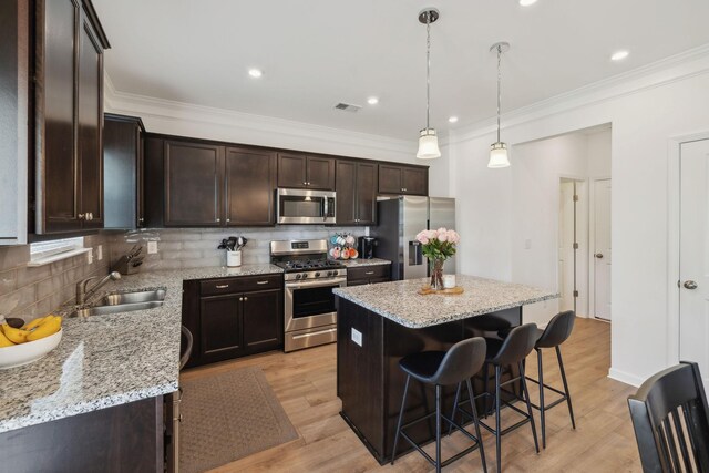 kitchen with stainless steel appliances, a breakfast bar, visible vents, a sink, and dark brown cabinetry