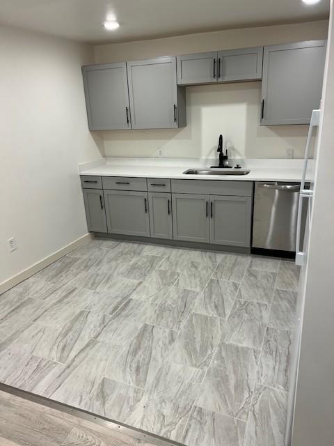 270 Tampa Dr Unit G16, Nashville, TN 37211 - kitchen featuring stainless steel dishwasher, a sink, gray cabinets, light countertops, and baseboards
