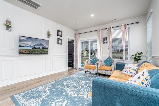 living area featuring visible vents, wood finished floors, recessed lighting, and a decorative wall