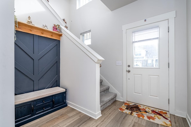 foyer featuring stairway, baseboards, light wood-style floors, and plenty of natural light