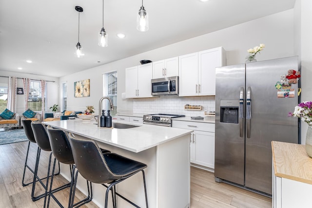 kitchen with decorative backsplash, stainless steel appliances, a sink, and light wood-type flooring