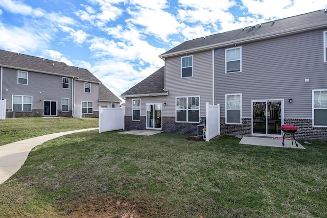 rear view of property with brick siding, a lawn, and a patio