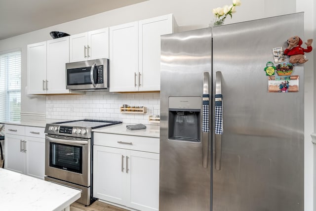 kitchen featuring decorative backsplash, appliances with stainless steel finishes, light wood-style floors, and white cabinets