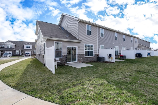 back of property with central air condition unit, a lawn, and fence