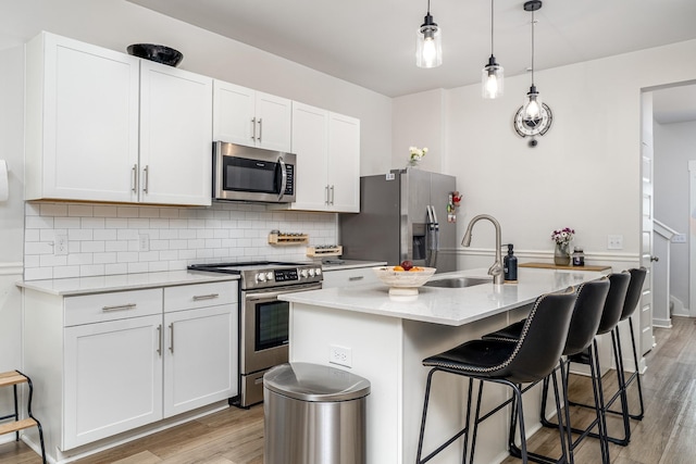 kitchen with tasteful backsplash, a sink, a breakfast bar area, stainless steel appliances, and light wood finished floors