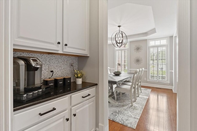 9502 Peebles Ct, Brentwood, TN 37027 - bar with light wood-type flooring, pendant lighting, baseboards, tasteful backsplash, and a notable chandelier