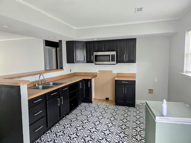 300 Hardin Ave, Dickson, TN 37055 - kitchen featuring stainless steel microwave, a sink, dark cabinets, backsplash, and ornamental molding