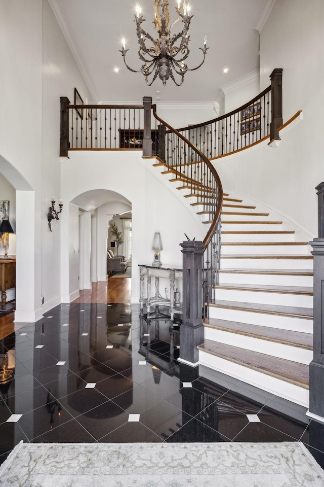 entryway with granite finish floor, a high ceiling, arched walkways, and ornamental molding