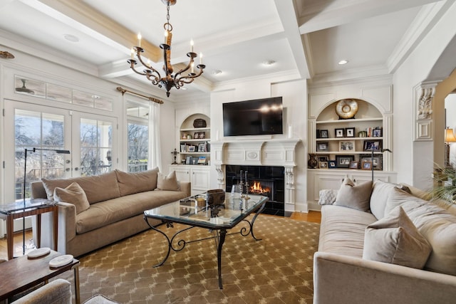 living room featuring built in shelves, a fireplace with flush hearth, an inviting chandelier, coffered ceiling, and ornamental molding