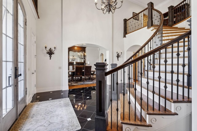 foyer entrance with arched walkways, a chandelier, stairway, and a high ceiling