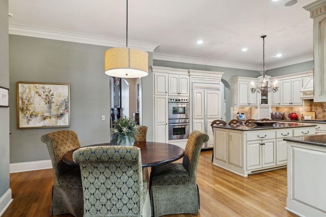 kitchen with a center island, light wood-style flooring, dark countertops, a chandelier, and double oven