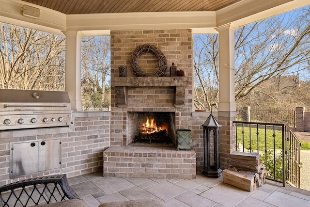 view of patio with area for grilling and an outdoor brick fireplace