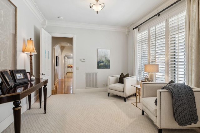 sitting room featuring arched walkways, light colored carpet, baseboards, ornamental molding, and visible vents