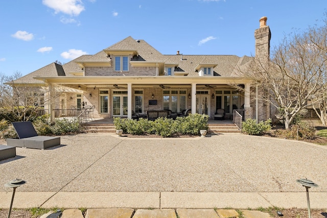 rear view of property with a chimney, a ceiling fan, french doors, a porch, and brick siding